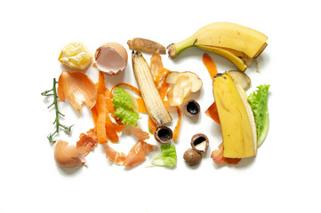 Different food waste on white background top view. Clean banana, egg shells, shells of nuts, cleaning onions carrots potatoes, bits of green salad and branches from the tomato.