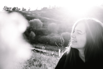 Obraz premium Portrait of beautiful brunette young girl in black clothes at sunset on background of hills. Copy space