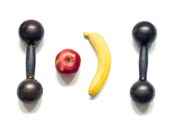 Two dumbbells Apple and banana on white background, top view. The concept of a healthy diet and a healthy lifestyle.