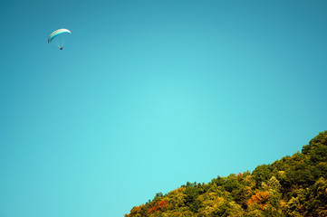 Paragliding in summer sun in European countryside near a mountain
