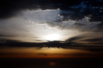 Fototapeta na wymiar Strong sun light rays striking from behind clouds at sunrise