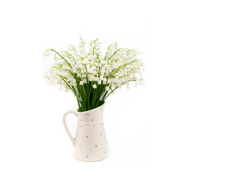 Bouquet of white flowers Lily of the valley (Convallaria majalis) also called: May bells, Our Lady's tears and Mary's tears in a white dotted jug shaped vase isolated on white.