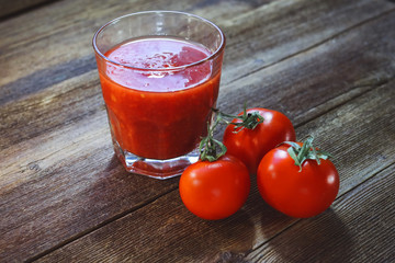 tomatoes and tomato smoothies in a glass on a wooden background.