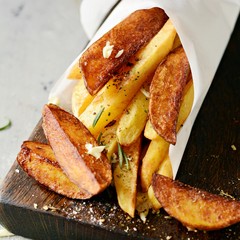 Potato food . Baked potatoes with spices and salt. Tasty french fries on cutting board with ketchup and tomato juice.