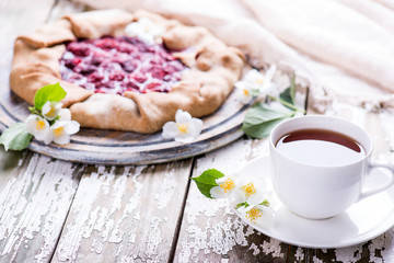 Obraz na płótnie Canvas Freshly homemade baked deliciouse strawberry pie with cup of tea on a wooden background. Copy space.