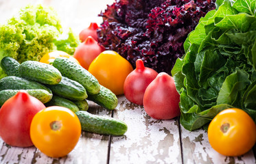 Natural fresh ingredient for cooking vegan salad - tomatoes, cucumber, lettuce on a wooden background. Copy space.