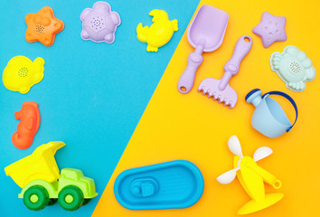 top view of the children's play set for sand, playing in the sandbox, at sea or in the park. Bright plastic, silicone toy set for kids. Flatlay with space for text on a bright yellow-blue background