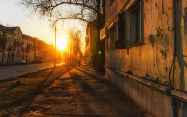 silhouette of man walking along city street during beautiful warm sunset.