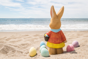 Fototapeta na wymiar Beach Easter background with bunny and color eggs