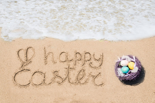 Happy easter lettering background with eggs on the sandy beach