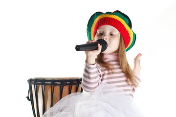 Joyful rastafarian toddler girl sinnging in a microphone and a drum