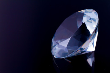 Fototapeta na wymiar A huge diamond on a black mirror surface with a reflection of a diamond