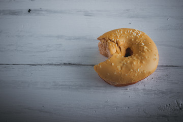 bitten delicious donut on a white wooden background