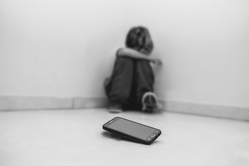 concept of cyber bulling. Child in school uniform crying in front of smartphone.