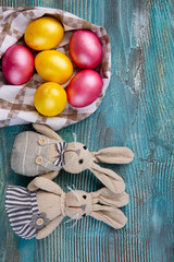 Fluffy foxy rabbits with Easter eggs on blue wooden background