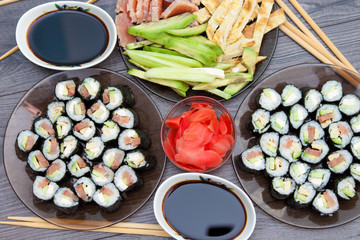 Sushi rolls set served on black stone plate on dark background. Flat lay, top view. Homemade japanese menu.