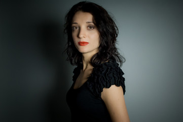 Studio portrait of sexy brunette woman with red sensual lips looking at the camera posing on black background