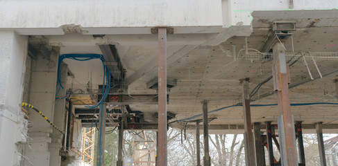 Naklejka premium heavy industrial stilts hold up a multi-story building while the ground floor is demolished and rebuilt