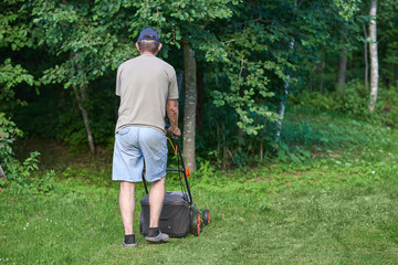 Country works on the personal plot using lawn mower. © Artem