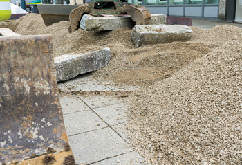 building a a stone wall with red granite during a landscape construction job with an excavator and clamp moving the large stones