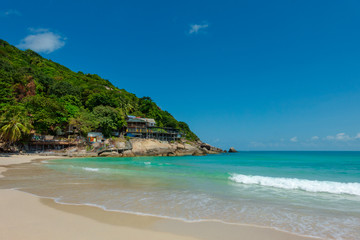 Fototapeta na wymiar White sandy tropical beach with calm wave and blue lagoon on sunny day