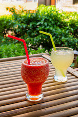 Watermelon and lemon iced smoothies in glass on bamboo table.
