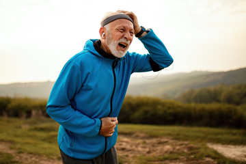 Naklejka premium Senior athlete feeling pain while working out in nature.