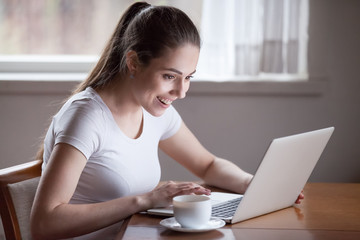 Excited woman reading good news on laptop screen at home