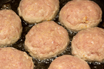 Raw cutlets are cooked in a pan.
