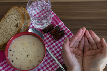 A cup of soup,bread ,date and water service on the wooden table for Ramadan ,thanksgiving. A little meal for diet. 