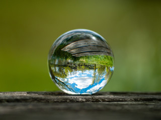 Landscape reflected in a crystal ball on an old wooden table