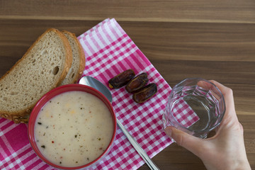 A cup of soup,bread ,date and water service on the wooden table for Ramadan ,thanksgiving. A little meal for diet. 