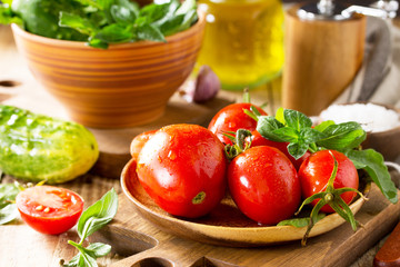 Healthy food: fresh vegetables on the kitchen wooden table. Fresh tomatoes, cucumbers and rucola for cooking salad. Diet menu.