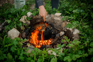 Close shot of man preparing food in pan on campfire