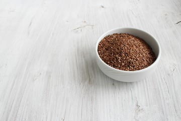 lax seeds in white bowl on white background. Rustic style.