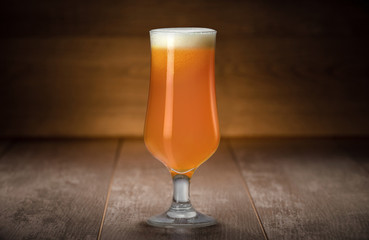 Golden unfiltered IPA from craft brewery, hazy juicy tropical beer against wood, colorful bright...