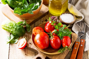 Healthy food: fresh vegetables on the kitchen wooden table. Fresh tomatoes, cucumbers and rucola for cooking salad. Diet menu. Copy space.