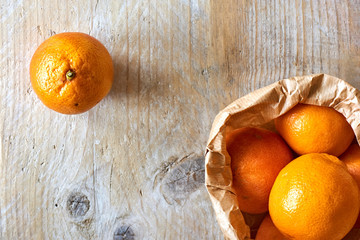 Orange organic blood oranges in brown paper bag on weathered wooden table with copy space flat lay