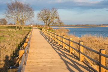 Pedestrian wooden bridge in the park. Place to rest near the lake. View of the park at sunset.