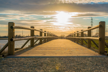 Fototapeta premium Pedestrian wooden bridge in the park. Place to rest near the lake. View of the park at sunset.