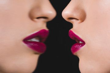 Obraz premium cropped view of woman with crimson lips near mirror isolated on black