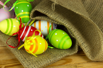 Fototapeta na wymiar colorful easter eggs on a wooden background under burlap