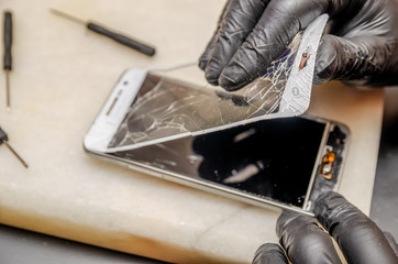 Technician or engineer opening broken smartphone for repair or replace new part on desk