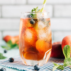 The glass of peach ice tea on wooden table. Cuba Libre or long island iced tea cocktail, cold drink...