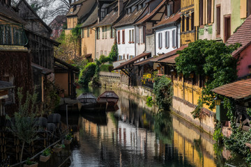 Fototapeta na wymiar Romantic cityscape. Old houses on the embankment along the canal. There are reflections of houses in the water. Spring morning City of Colmar, Alsace. France.