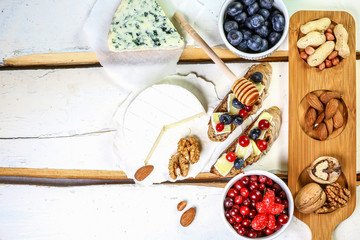 Fruit Bruschetta with cheese, fresh berries, walnuts, against a white background. Flat lay. copy text