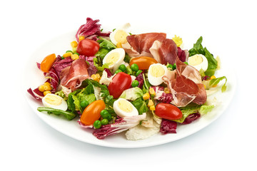 Healthy fresh salad of tomatoes, jamon, frisee, rucola and quail eggs, organic food, close-up, isolated on white background