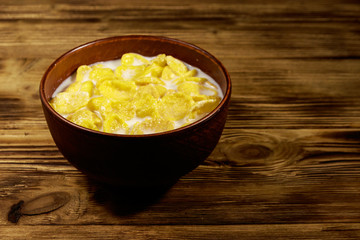 Cornflakes with milk in a bowl on wooden table
