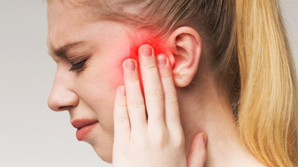 Young woman has sore ear, suffering from otitis