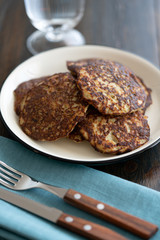 Potato pancakes draniki served on a white plate. Dark wooden table, blue linen napkin, high resolution